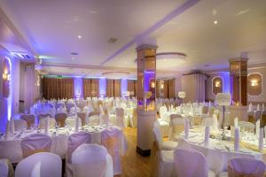 Un salón de banquetes con mesas y sillas blancas. en Oranmore Lodge Hotel Conference And Leisure Centre Galway, en Oranmore