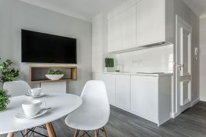 a white kitchen with a white table and chairs at VIU Indigo Apartments in Gdańsk