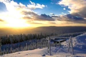 a view of a snow covered mountain with the sun setting at Wurmberg Domizil in Braunlage