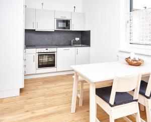 a white kitchen with a white table and chairs at Krug-Apartments in Ebelsbach