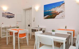 a dining room with white tables and chairs and a painting on the wall at Alta Marea B&B in Porto Empedocle