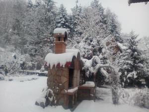 una chimenea de ladrillo cubierta de nieve en un patio en Pensiunea Paradis, en Borobăneşti