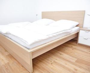 a bed with white sheets and a wooden frame in a room at Krug-Apartments in Ebelsbach