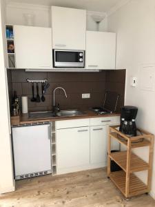 a kitchen with white cabinets and a sink and a microwave at Ferienwohnung Liebing in Bad Sachsa