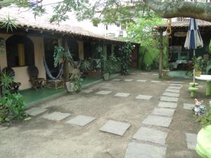 a patio in front of a house with a tree at Suítes Brisa Mar in Cabo Frio