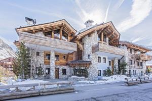 a large wooden house with snow on the ground at Chalet Papillon - LES CHALETS COVAREL in Val dʼIsère