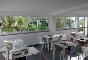 un restaurant avec des tables blanches, des chaises et des fenêtres dans l'établissement Oasi Di Casablanca, à Lampedusa