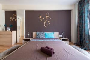 Un dormitorio con una cama grande con almohadas moradas. en City Apartments, en Sofía