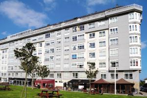 ein großes weißes Gebäude mit Picknicktischen davor in der Unterkunft Duerming Park Viveiro in Viveiro