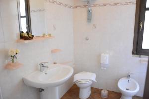 La salle de bains blanche est pourvue d'un lavabo et de toilettes. dans l'établissement Hotel Funtana Noa, à Villanovaforru