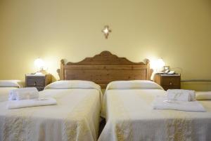 1 dormitorio con 3 camas y ropa de cama blanca en Hotel Funtana Noa en Villanovaforru