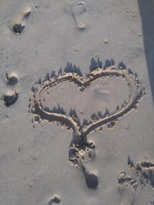 un corazón dibujado en la arena de la playa en La petite campagne, en Le Moule