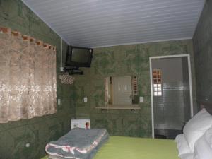a bedroom with a bed and a tv on the wall at Pousada Tia Lilía in Gonçalves
