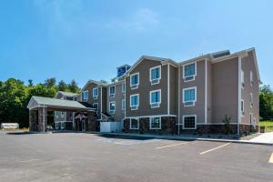 a large apartment building with a parking lot at Cobblestone Hotel & Suites - Greenville in Greenville