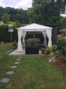 a white gazebo with a table and chairs in a garden at Ferienwohnung Liebing in Bad Sachsa