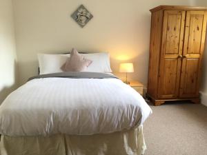 um quarto com uma cama branca e um armário de madeira em Spacious 3 Bedroom Apartment em Saint Albans