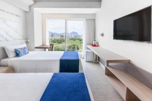 a hotel room with a large bed and a television at Ramada Encore by Wyndham Rio de Janeiro Ribalta in Rio de Janeiro