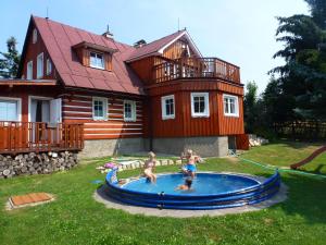 three children playing in a pool in front of a house at Apartmány Pelíšek in Harrachov