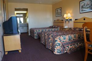 a hotel room with two beds and a flat screen tv at Delux Inn Tulsa in Tulsa