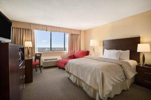 ティミンズにあるThe Senator Hotel & Conference Center Timminsのベッドと赤い椅子が備わるホテルルームです。
