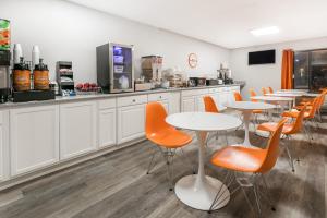 eine Cafeteria mit Tischen, orangen Stühlen und einer Theke in der Unterkunft Howard Johnson by Wyndham Scott Lafayette in Scott