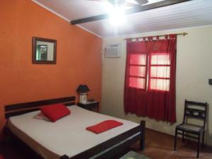 a bedroom with a bed and a red window at Suítes Brisa Mar in Cabo Frio