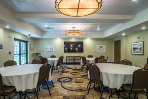 Cobblestone Inn & Suites - St Marys في Saint Marys: قاعة اجتماعات مع طاولات وكراسي وشاشة عرض