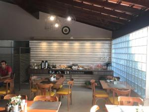 a dining room with tables and chairs and a kitchen at Hotel Itamarati in Uberlândia