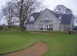 une maison avec une pelouse verte devant elle dans l'établissement Clogher Valley Golf Club, à Fivemiletown