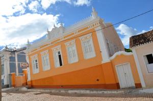 an orange building with white windows on a street at Hotel e Pousada O Casarão in Palmeiras