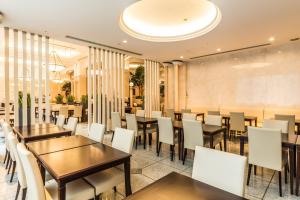 東京にあるホテルマイステイズプレミア大森の木製テーブルと白い椅子が備わるレストラン