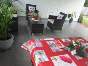 a room with chairs and a table with a red blanket at Villa Bananier in Lamentin