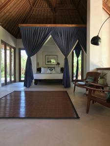 a bedroom with a bed with blue drapes at Villa Samudera in Nusa Lembongan