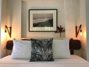 a bed with white pillows and a picture on the wall at Villa Samudera in Nusa Lembongan