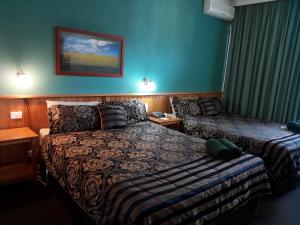 una camera d'albergo con due letti e un letto e una gonna da letto di Moe Motor Inn - Contactless 24 hour Checkinn Available a Moe