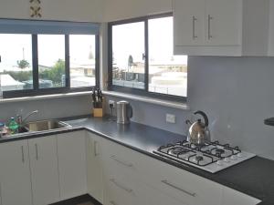a kitchen with white cabinets and a stove top oven at The Jewel of the Bay in Smoky Bay