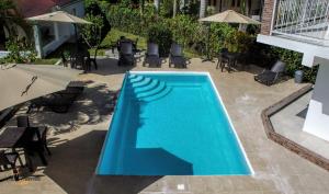 a large blue swimming pool with tables and chairs at Hotel Casa Pierretta in Las Terrenas