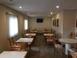 une salle à manger avec des tables, des chaises et une télévision dans l'établissement Grand Hotel Taboao, à Taboão da Serra