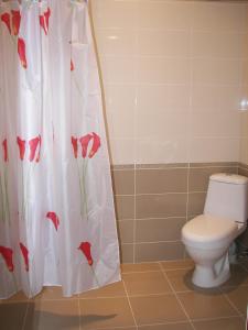a bathroom with a toilet and a shower curtain with red flowers at Hotel MIRA in Goris