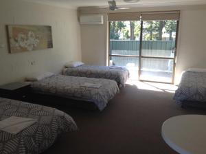 a bedroom with two beds and two windows at Settlers Inn in Port Macquarie