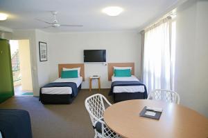 a hotel room with two beds and a table at Darcy Arms Hotel Motel in Gold Coast
