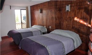 two beds in a room with wooden walls at Hotel Avenida in Zacatl&aacute;n