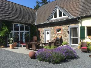 a house with a table and chairs and purple flowers at Grimmershof in Hürtgenwald