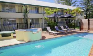 a swimming pool with chairs and umbrellas next to a building at Darcy Arms Hotel Motel in Gold Coast