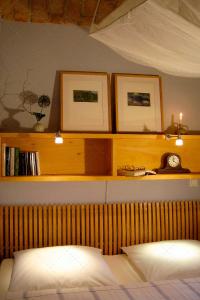 a shelf above a bed with two pictures and a clock at JANISCHs Fewo im Spreewald in Neu Lübbenau