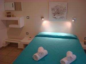 una camera da letto con un letto verde e asciugamani di Smaragdi Studios and Rooms ad Agios Kirykos