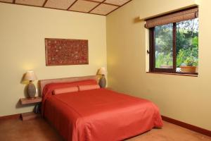 a bedroom with a red bed and a window at La Hacienda Mauritius in Mahébourg