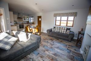 a living room with two couches and a kitchen at Millmoor Farm Holidays in Malpas