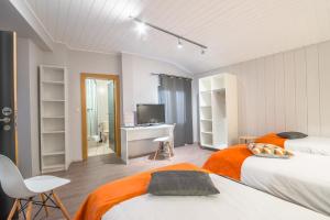 Un dormitorio con dos camas y un escritorio y un televisor. en Mandarina Hotel Luxembourg Strassen, en Luxemburgo