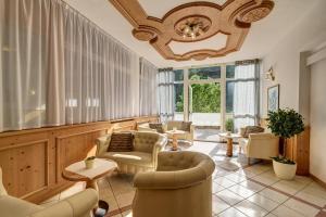 - un salon avec des chaises et un lustre dans l'établissement Aparthotel Wellness Villa di Bosco, à Tesero